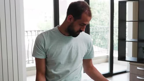 Young Creative Director Sitting on His Office Desk Checking Some Notes and Working on Laptop