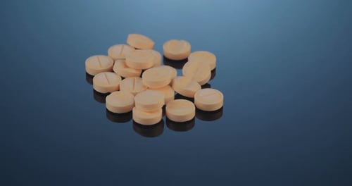 Pile of Beige Pills Rotating on Dark Surface