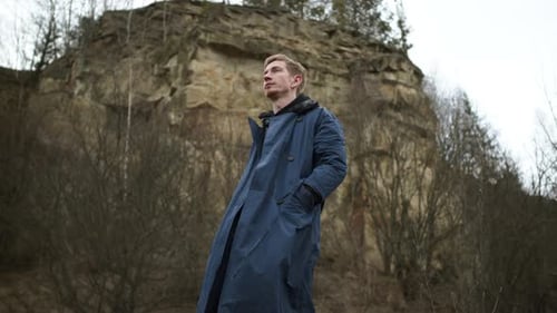 Handsome Young Guy Standing Near Rock. Stylish Redheaded Boy With Beard And Ear Piercing.
