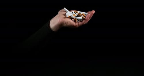 Hand of Man and Broken Cigarettes on Black Background, Slow Motion 4K