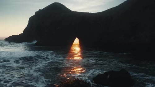 Cinematic Golden Sun Beam Coming Through Natural Arch or Hole in Rock or Island