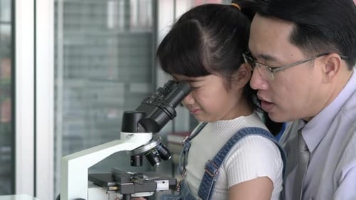 Man and kid girl looking microscope