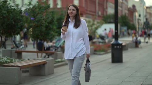 Woman Walking and Drinking Coffee in City