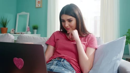 Young Woman Using Laptop on Sofa at Home