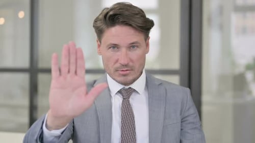 Man in Suit Holds Up Hand in Stop Gesture