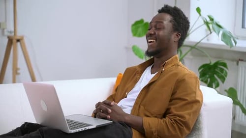 Man Smiling While Using Laptop on Couch