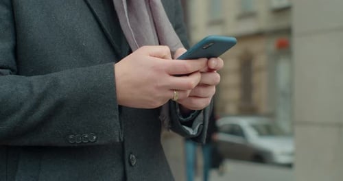 Close Up of Man’s Hands of Young Businessman Using His Smartphone. He’s Texting Messages While