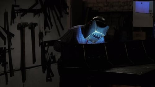 A Welder in a Factory Works Welding Sparks in the Dark Manufacturing