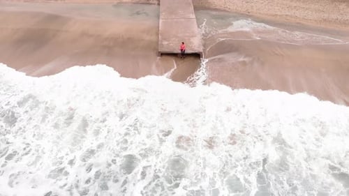 Lonely person is sitting at edge of pier. Loneliness and freedom