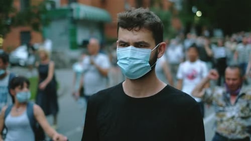 Man in Mask Walks Through Crowd in City