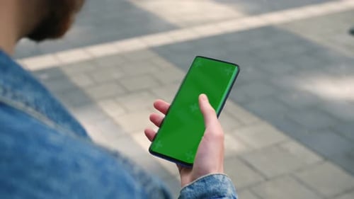 View From Shoulder of Caucasian Man Doing Swipe Up Gesture on Chroma Key of Modern Smartphone