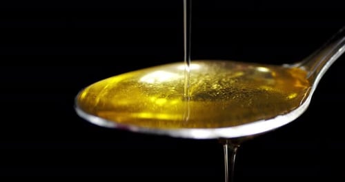 Olive Oil Flows in a Thin Stream Into the Spoon.
