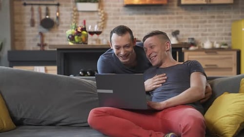 Smiling Couple Relaxing at Home with Laptop