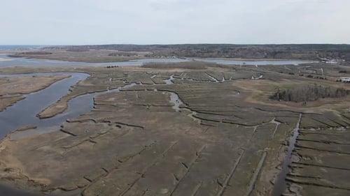 Slow drone push forward over the driftway marshes in Scituate, MA USA. Springtime, half tide. Daytim