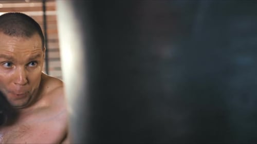 Young Boxer is Exercising with a Punching Bag at the Gym