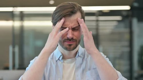 Man Rubbing Temples in Office Setting