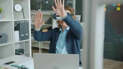 Slow Motion of Guy Wearing Virtual Reality Glasses Moving Arms in Office at Desk