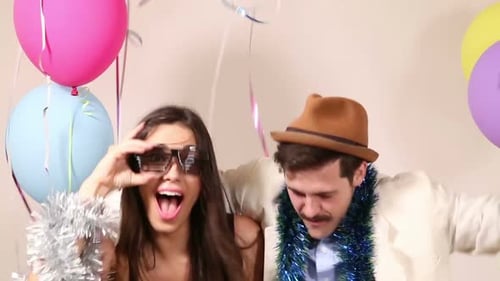 Happy man and woman having a great time in party photo booth