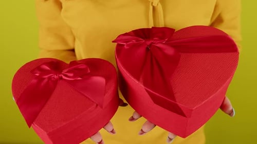 Holding Two Heart Shaped Gifts with Red Ribbons