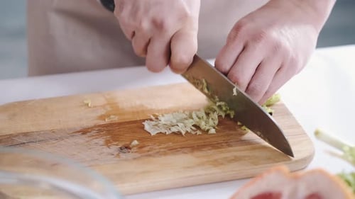 Chopping Fresh Greens with Knife on Wood Board