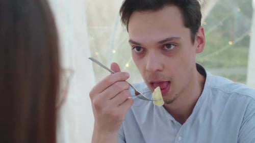Man Eats Food with Companion at Restaurant
