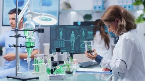 Female Biologist Looking at Plant Samples and Taking Notes