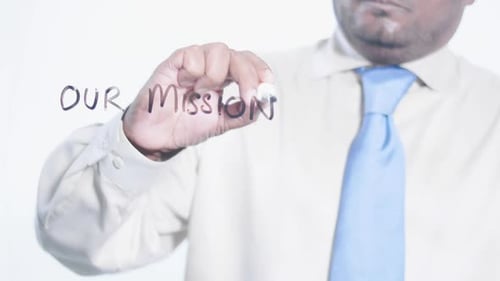 Man Writing 'Our Mission' on Transparent Surface