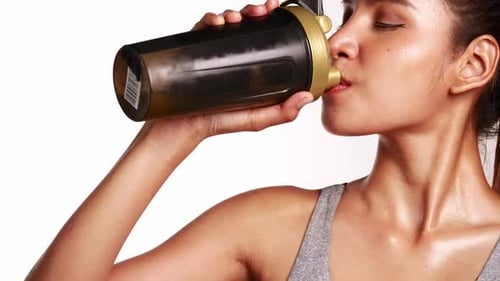 woman in sportswear drinking a whey protein supplement for fitness and diet to control