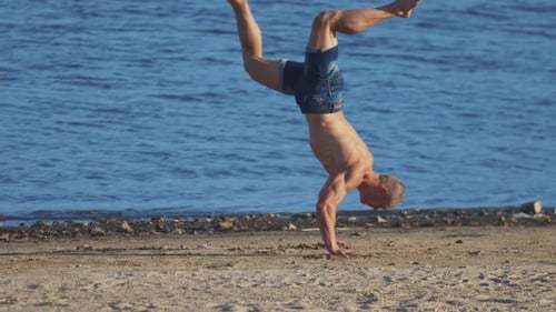Sports Exercises Outdoors Young Fit Man Performing a Backflip on the Beach
