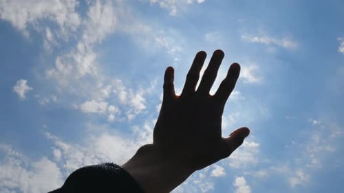 Hand Reaching for Sunny Sky with Clouds