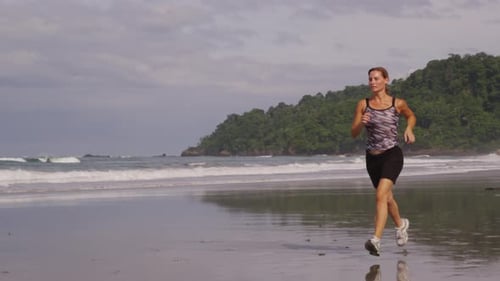Woman out for early morning run on beach. Shot on RED EPIC for high quality 4K, UHD, Ultra HD resolu
