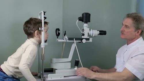 Eye Doctor Examines Child's Eyes with Ophthalmic Instrument