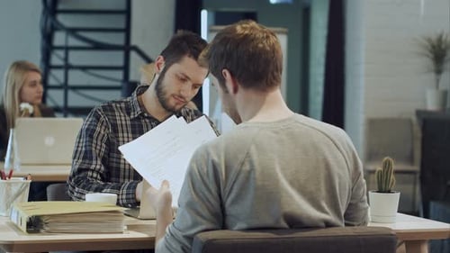 Two Men Discussing Documents in Office Setting