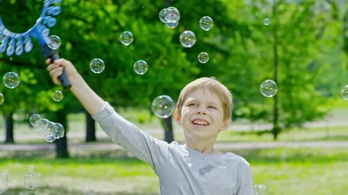 Playful Boy Swinging Wand and Making Soap Bubbles in Park