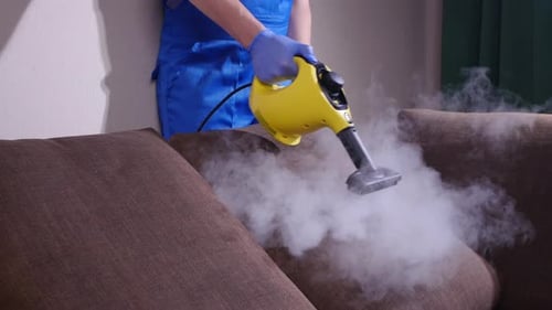 Professional Cleaner Steams Couch with Cleaning Appliance