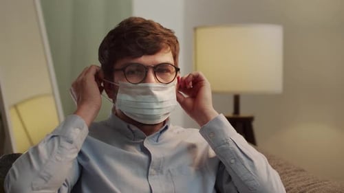 Man Puts on a Disposable Medical Face Mask