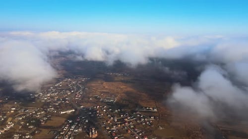 Aerial View From High Altitude of Distant City Covered with Puffy Cumulus Clouds Forming Before