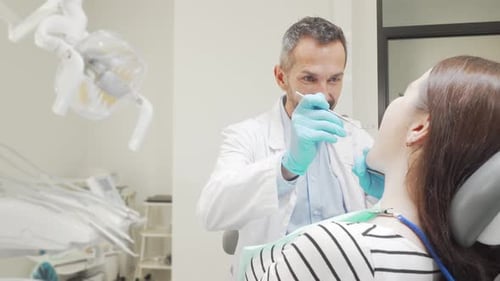 Mature Male Dentist Examining Teeth of a Female Patient