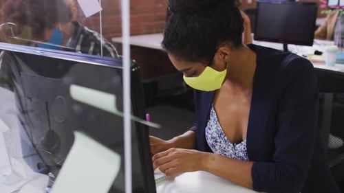 Woman with Face Mask Writes Note at Office