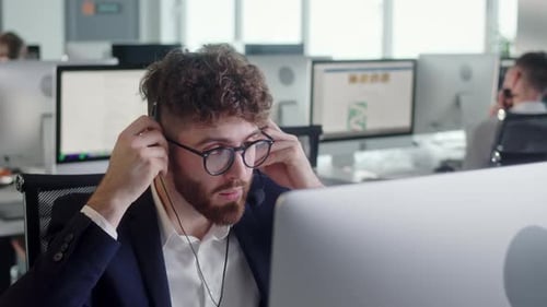 Close Up Portrait of a Technical Customer Support Specialist Talking on a Headset While Working on a