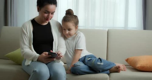 Woman and Girl Viewing Phone on Sofa