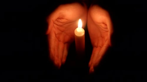 Manos sosteniendo una vela encendida en la oscuridad 003