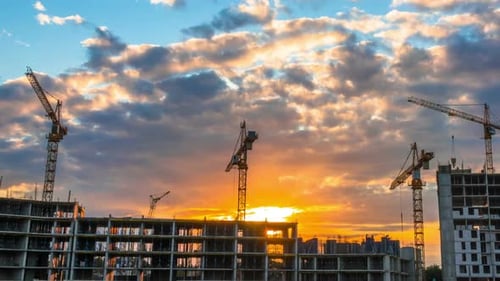 Cranes at Construction Site Moving at Sunset