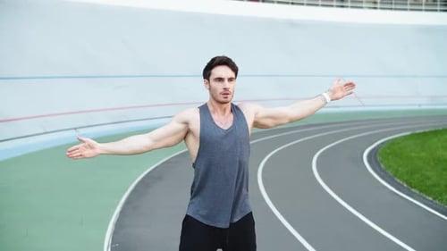 Male Runner Warming Up Before Running Workout on Track. Fit Man Stretching Hands
