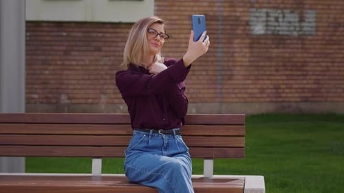 Woman taking selfie photo on smartphone in park city