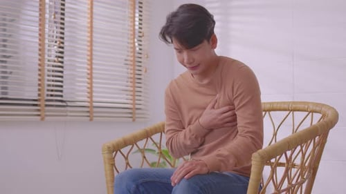 Asian man suffered a heart attack, resulting in chest pain and illness on the sofa.