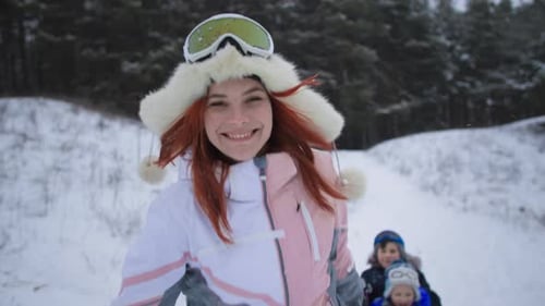 Woman Pulling Children on Sled Through Snowy Forest