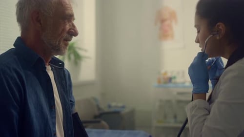 Woman Therapist Checking Pulse Elderly Patient in Clinic Using Stethoscope