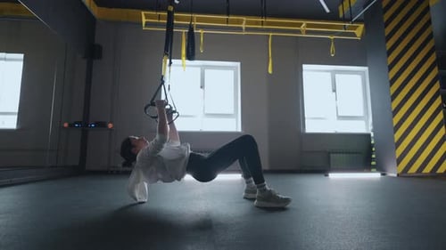 Sporty Woman Doing TRX Exercises in the Gym