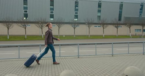 A Young Guy Is Walking with a Suitcase Near Airport and Looking at His Watch, Travel By Plane